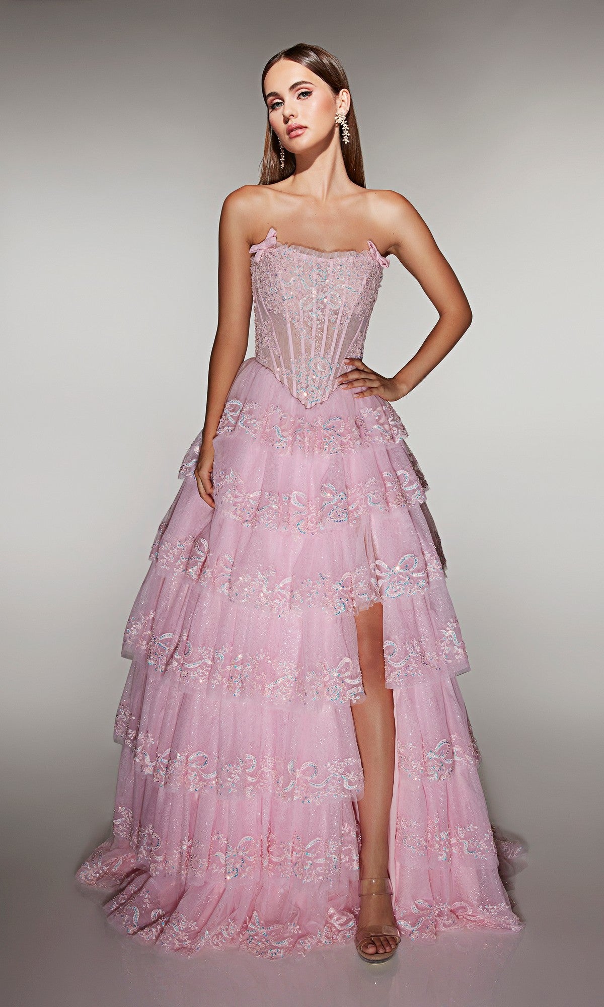 A woman stands facing forward against a plain background, wearing the Alyce 62191 long prom dress featuring a strapless embellished corset bodice and a pink tiered A-line skirt with floral embroidery.